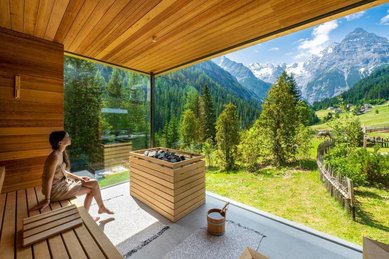In der Sauna des Familienhotel Bella Vista in Südtirol genießt ein Gast den Blick durch große Panoramafenster auf die Berge.
