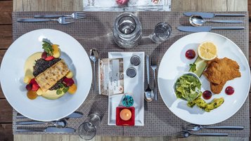 Abwechslungsreich gedeckter Esstisch mit Fischfilet und Schnitzel im Familienhotel Ramsi.