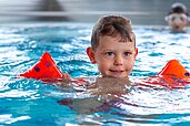 Ein Junge planscht mit Schwimmflügeln im Indoor-Pool des Hotels Alpengasthof Hochegger.