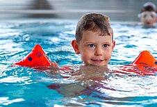 Ein Junge planscht mit Schwimmflügeln im Indoor-Pool des Hotels Alpengasthof Hochegger.