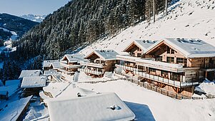 Gemütliche Chalets des Familienhotels Alphotel in Tyrol, eingebettet im Schnee. 