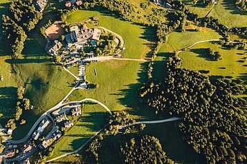 Luftaufnahme des Familienhotels Kirchheimerhof in Kärnten. Das Familienhotel befindet sich mitten im Grün.