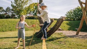 Das Mädchen übt sich auf der Slackline des Spielplatzes vom Familienhotel Strandkind.