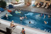 Familien im Außenpool des Familienhotels Bruckwirt in Oberösterreich bei schönen Wetter im Sommer.