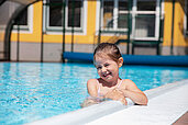 Lachendes Mädchen im Außenpool des Familienhotels Bruckwirt in Oberösterreich bei schönen Wetter im Sommer.