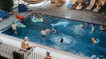 Familien im Außenpool des Familienhotels Bruckwirt in Oberösterreich bei schönen Wetter im Sommer.