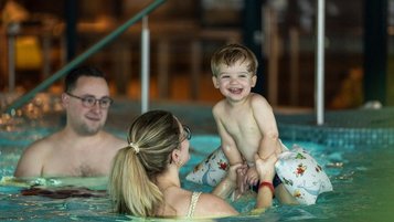 Fröhliche Familienzeit im Wasser: Im Familienhotel Elldus im Erzgebirge planschen Eltern mit ihrem Kleinkind im Pool.