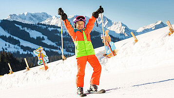 Kind steht auf der Skipiste im familienfreundlichen Skigebiet im Familienurlaub in Bayern.