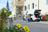 Familie parkt vor dem Hoteleingang des Familienhotels Rhön Feeling und räumt das Auto aus.