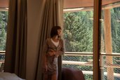 Frau steht am Balkon im Hotel Bella Vista in Südtirol und blickt in den Wald.