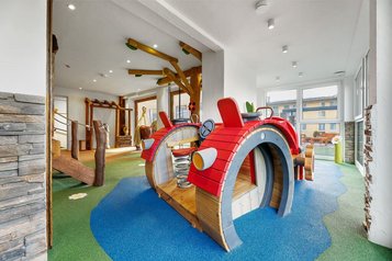 Bunter Indoor-Spielbereich mit Holzspielgeräten und Traktor-Kletterelement für Kinder im Hotel Engel im Schwarzwald