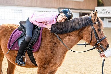 Mädchen sitzt auf einem Pferd im Reitunterricht im Familienhotel Sonnenpark.