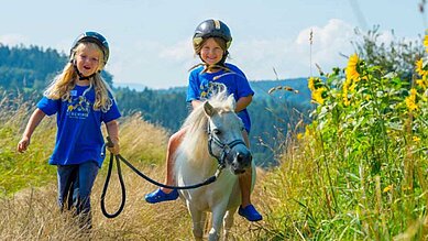 Kinder erkunden die unberührte Natur des Bayerischen Waldes beim Ponyreiten im Familienurlaub im Familienhotel Ulrichshof.