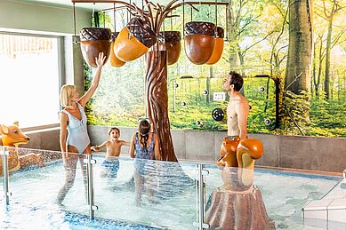 Eltern spielen mit ihren Kindern im Kinderschwimmbecken im Familienhotel Das Bayrischzell in Oberbayern.