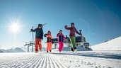 Eltern und Kinder genießen gemeinsam sonnige Skitage auf perfekt präparierten Pisten rund um das Familienhotel Ramsi in Kärnten