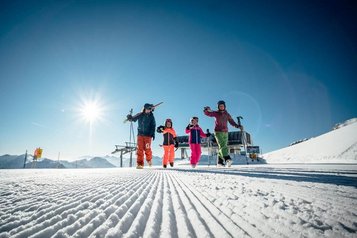 Eltern und Kinder genießen gemeinsam sonnige Skitage auf perfekt präparierten Pisten rund um das Familienhotel Ramsi in Kärnten