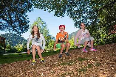 Ein paar Teenager sitzen auf einer Slackline auf dem Außengelände des Spa- & Familien-Resorts Krone im Allgäu.