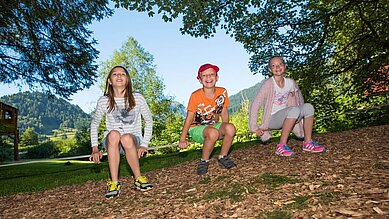 Ein paar Teenager sitzen auf einer Slackline im Spa- & Familien-Resort Krone im Allgäu