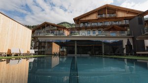 Blick auf das Familienhotel Scherer mit beheiztem Outdoor-Pool und moderner Holzarchitektur.