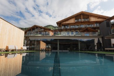 Blick auf das Familienhotel Scherer mit beheiztem Outdoor-Pool und moderner Holzarchitektur.