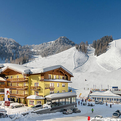 Das Familienhotel Zauchenseehof im Salzburger Land umgeben von einer verschneiten Landschaft. Das Hotel liegt direkt am familienfreundlichen Skigebiet.