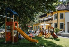 Ein Spielplatz mit Rutsche vor dem Kinderhotel Bruckwirt in Oberösterreich.