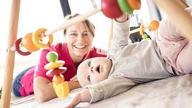 Kleinkind spielt in der Babybetreuung des Allgäuer Berghofs mit der Kinderbetreuuerin.
