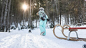 Oberösterreich im Winter erleben: Herrliche Winterlandschaft in Pyhrn Priel Hinterstoder. Kind zieht einen Schlitten hinter sich den Berg hoch und freut sich auf das gemeinsame Rodeln.