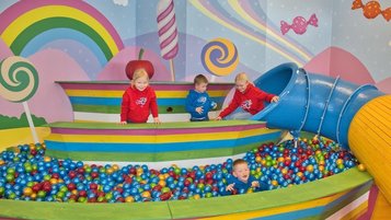Fröhlicher Indoor-Spielbereich mit großem Bällebad, Rutsche und Candyland-Design – perfekt für Spaß, Bewegung und fantasievolles Spielen.