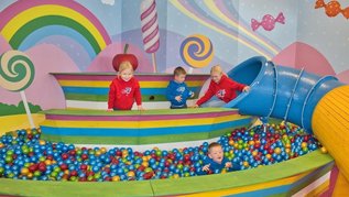 Fröhlicher Indoor-Spielbereich mit großem Bällebad, Rutsche und Candyland-Design – perfekt für Spaß, Bewegung und fantasievolles Spielen.