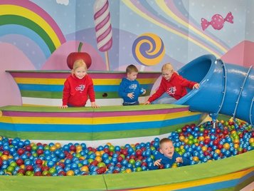 Fröhlicher Indoor-Spielbereich mit großem Bällebad, Rutsche und Candyland-Design – perfekt für Spaß, Bewegung und fantasievolles Spielen.