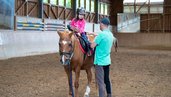 Ein Kind nimmt eine Ritstunde im Familienhotel Der Ponyhof in der Steiermark.