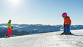 Familie in Kaernten im Winter beim Skifahren. Der Katschberg mit Sonne und blauem Himmel.