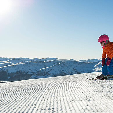 Familie in Kaernten im Winter beim Skifahren. Der Katschberg mit Sonne und blauem Himmel.
