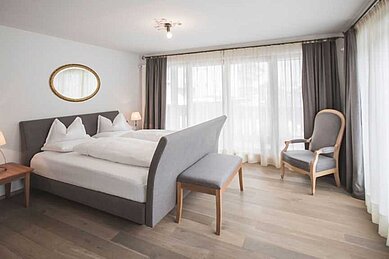 Ein Zimmer mit Bett und Balkon im Familienhotel Alpenhof Dolomit Family in Südtirol.