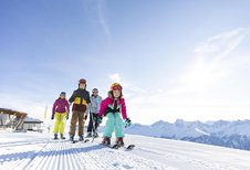 Familie auf der Piste beim Skifahren bei wundervollem Wetter in Tirol in der Nähe vom Adler Familien- & Wohlfühlhotel.