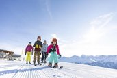 Familie auf der Piste beim Skifahren bei wundervollem Wetter in Tirol in der Nähe vom Adler Familien- & Wohlfühlhotel.