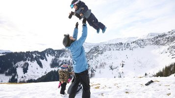 Winterlicher Familienspaß im Schnee beim Familienhotel Das Bayrischzell mit Blick auf die verschneiten Berge