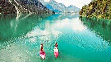 Zwei Stand-Up-Paddler auf dem Heiterwangersee in der Nähe des Familienhotels Kaiserhof in Berwang in der Tiroler Zugspitzarena