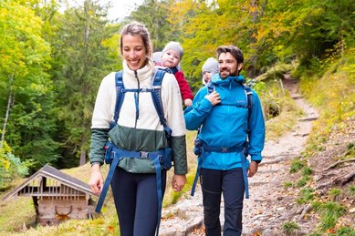 Junge Familie mit zwei Kleinkindern beim Wandern im Herbst im Familienurlaub in Oberbayern.