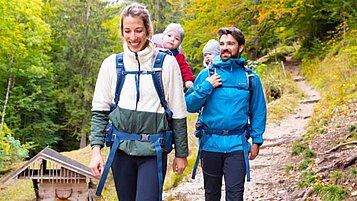 Junge Familie mit zwei Kleinkindern beim Wandern im Herbst im Familienurlaub in Oberbayern.