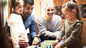 Familie mit zwei Kindern spielt ein Brettspiel