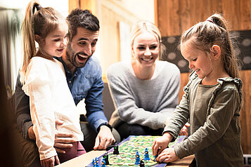 Familie mit zwei Kindern spielt ein Brettspiel