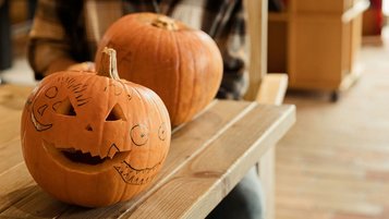 Zwei zu Halloween geschnitzte Kürbisse auf einem Holztisch 