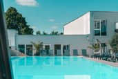 Moderner Außenpool mit Liegebereich und Palmen im Familienhotel Friedrichshof.