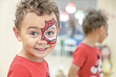 Ein kleiner Junge lässt sich im Happy-Club das Gesicht bemalen im Familienhotel Gorfion in Lichtenstein.