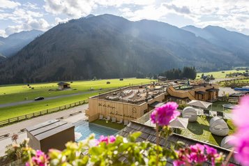 Luftaufnahme des Familienhotels Almfamilyhotel Scherer mit Pool, Sonnenterrasse und Blick auf die umliegenden Berge.