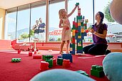 Kinder bauen aus Bauklötzen einen Turm im Happy-Club im Familienhotel Amiamo im Salzburger Land.