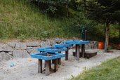 Ein Wasserspielbereich mit blauen Rinnen in einem Sandbereich im Außenareal des Kinderhotels Bruckwirt in Oberösterreich.