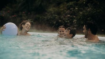 Eine Familie genießt gemeinsam Zeit im Außenpool des Hotel Sonngastein im Salzburger Land.